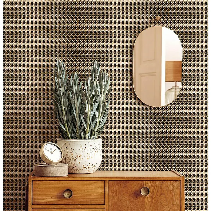 Marburg Struktura Vliestapete Holzgeflecht - Braun/Beige, Holzoptik, 10,05 x 0,53 m - Nahaufnahme eines Zimmers mit Rattan-Tapete, einer Kommode, einer Pflanze, einer Uhr und einem Spiegel.