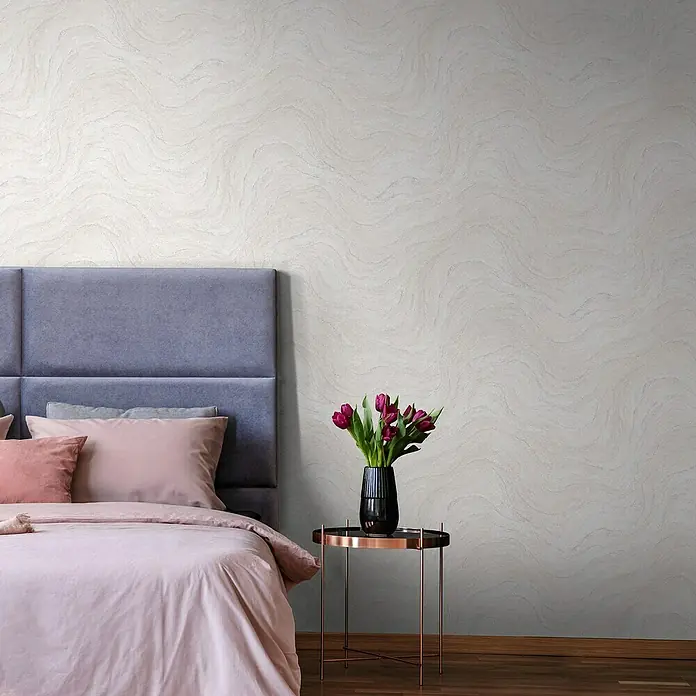 Marburg Struktura Vliestapete Marmoroptik - Grau/Rosa, Steinoptik, 10,05 x 0,53 m - Schlafzimmer mit Bett, Nachttisch und Vase mit Blumen vor einer strukturierten Wandtapete in Marmoroptik.