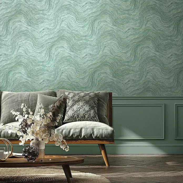 Marburg Struktura Vliestapete Marmoroptik - Grün, Steinoptik, 10,05 x 0,53 m - Elegantes Wohnzimmer mit grüner Wandtapete mit gewelltem Muster, passender Wandvertäfelung und stilvollem Sofa mit Kissen.