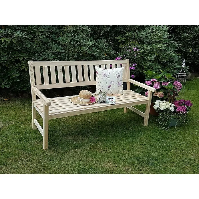 Promadino Gartenbank Johanna - B x T x H: 154 x 71 x 88,5 cm, Kiefer, Natur - Eine unbehandelte Holzgartenbank mit Kissen, Hut und Buch auf einer grünen Rasenfläche, umgeben von Pflanzen.