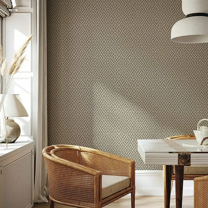 Marburg Struktura Vliestapete 3D-Rauten - Beige/Grau, 3D-Optik, 10,05 x 0,53 m - Einrichtung mit Rattansessel und beigem Teppich. Der strukturierte Teppich verleiht dem Raum eine warme und einladende Atmosphäre.