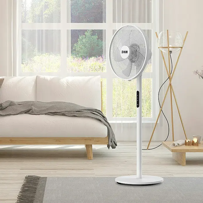 HJM Ventilador de pie VP586 - Blanco - Un ventilador de pie blanco HJM en una habitación luminosa con sofá y ventana, ofreciendo una brisa refrescante.