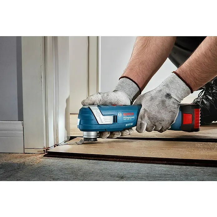 Bosch Professional AMPShare 18V Akku-Multifunktionswerkzeug GOP 18V-34 - 18 V, Ohne Akku - Ein Handwerker verwendet ein blaues Bosch GOP 18V-34 Multifunktionswerkzeug zum Schneiden von Holz. Präzision und Leistung in einem Gerät.