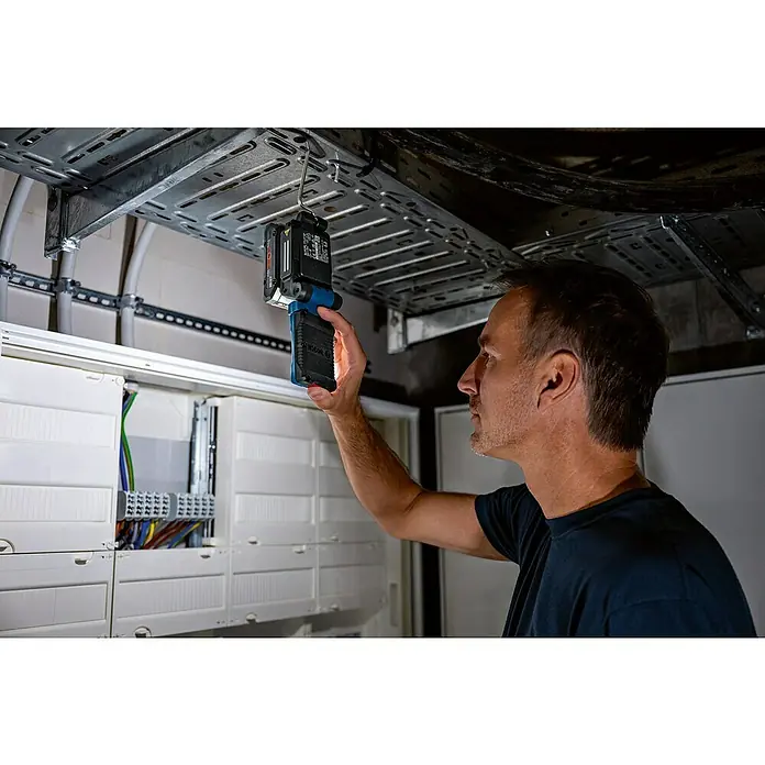 Bosch Professional AMPShare 18V LED-Akkustrahler GLI 18V-800 - 18 V, Ohne Akku, Lichtstrom: 800 lm - Ein Handwerker, der mit einer Bosch Arbeitsleuchte eine Schalttafel beleuchtet, um elektrische Arbeiten auszuführen.