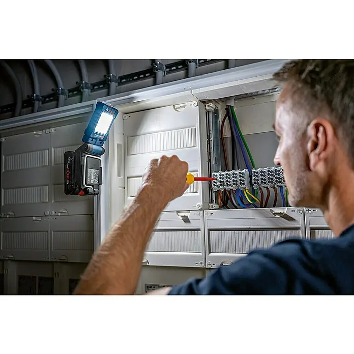 Bosch Professional AMPShare 18V LED-Akkustrahler GLI 18V-800 - 18 V, Ohne Akku, Lichtstrom: 800 lm - Ein Elektriker, der mit einem Bosch-Akku-Strahler eine elektrische Installation überprüft und eine optimale Beleuchtung sicherstellt.