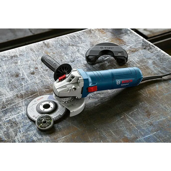 Bosch Professional Amoladora angular eléctrica PROFGWS12-125 - 1.200 W, Diámetro disco: 125 mm - Una amoladora angular inalámbrica Bosch Professional GWS 12V-76 con disco de amolar y accesorios en un banco de trabajo. La herramienta eléctrica es azul y gris.