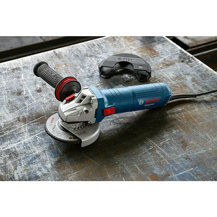 Bosch Professional Elektro-Winkelschleifer GWS 12-125 - 1.200 W, Durchmesser Scheibe: 125 mm - Nahaufnahme eines blauen Bosch Winkelschleifers mit Zubehör auf einer Werkbank.