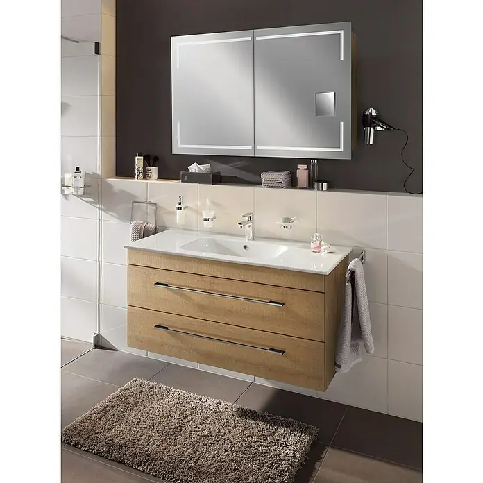 Lanzet K5 Badmöbel-Set K51B2 - 117,9 cm, Berg Eiche - Modernes Badezimmer-Interieur mit einem Waschtischunterschrank in Holzoptik, einem Spiegelschrank mit Beleuchtung und einer stilvollen Badematte.