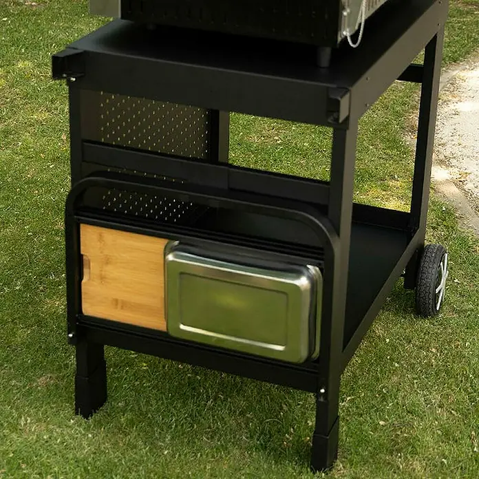 Mesa de barbacoa Reva 110 Premium para barbacoa - L x An x Al: 65 x 121 x 110 cm - Primer plano del carro de parrilla negro con tabla de madera y recipiente metálico para utensilios de parrilla. Práctico y elegante.