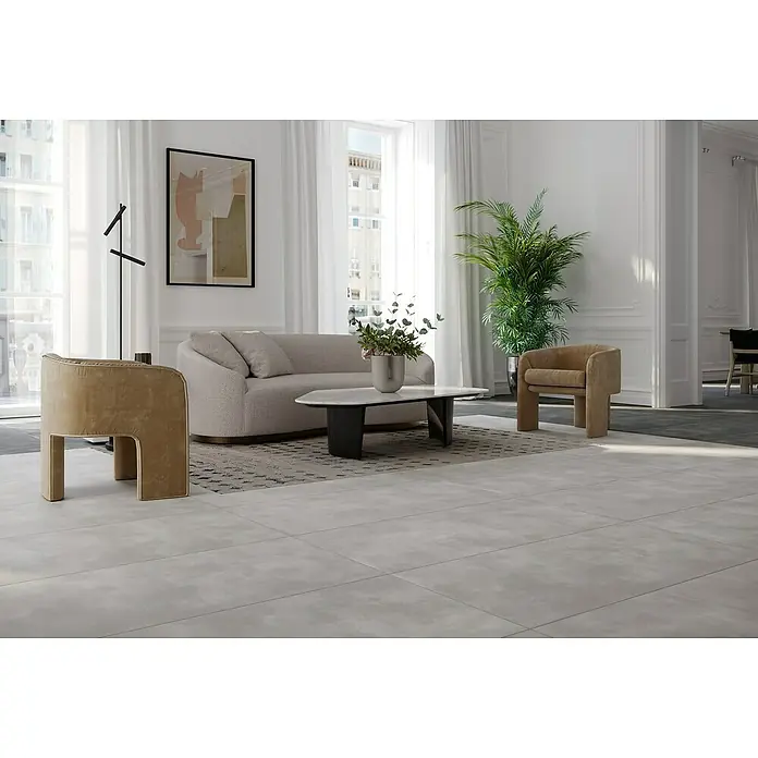 Feinsteinzeugfliese Big Show XXL - 59,8 x 119,8 cm, Grau, Matt - Elegantes Wohnzimmer mit beigem Sofa, modernem Sessel und einem Marmor-Couchtisch auf einem stilvollen Teppich. Das helle Interieur wird durch eine Zimmerpflanze ergänzt.