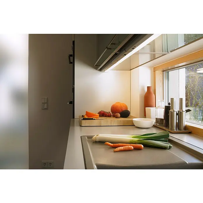 Osram Linear LED-Unterbauleuchte LED Flat - 6 W, Länge: 370 mm, Warmweiß - Helle Küche mit frischem Gemüse auf der Arbeitsplatte, darunter Lauch und Karotten, sowie Kürbis und Tomaten auf einem Schneidebrett.