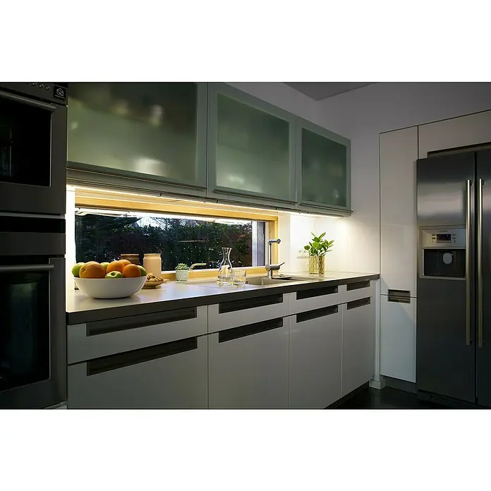 Osram LED-Unterbauleuchte LED Flat - 12 W, Länge: 52,7 cm, Warmweiß - Helle Küche mit Spüle unter dem Fenster und modernen Schränken. Blickfang sind die Unterbaulampen, die die Arbeitsfläche optimal beleuchten.