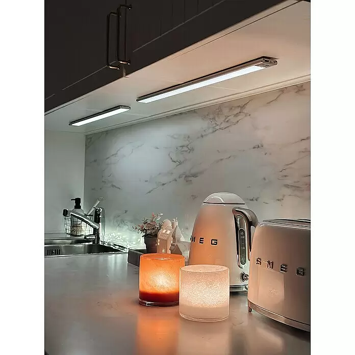 Osram Linear LED-Unterbauleuchte Flat USB & Sensor - L x B x H: 40 x 4 x 0,93 cm, Lichtfarbe: Warmweiß - Moderne Unterschrankleuchten erhellen eine Küchentheke und betonen leuchtende orange und weiße Votive, einen weißen Smeg Wasserkocher und Toaster.