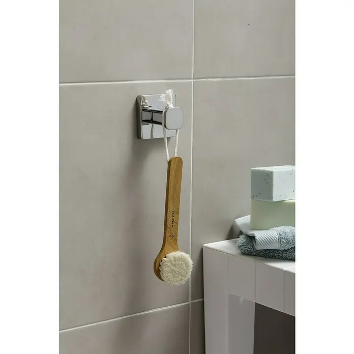 Tatay Kalo Colgador de baño - Cromo - Primer plano de un cepillo corporal con mango de madera colgando de un gancho cromado en una pared de baño gris.