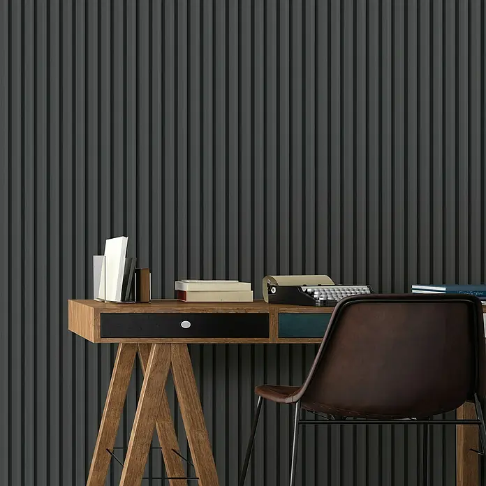 FN Neuhofer Wandpaneel Wally WA090 - Eiche schwarz, 2.670 x 118 x 12 mm - Schreibtisch mit Schreibmaschine, Büchern und Büromaterial vor einer Wand mit vertikalen Streifen. Der Stuhl steht davor.