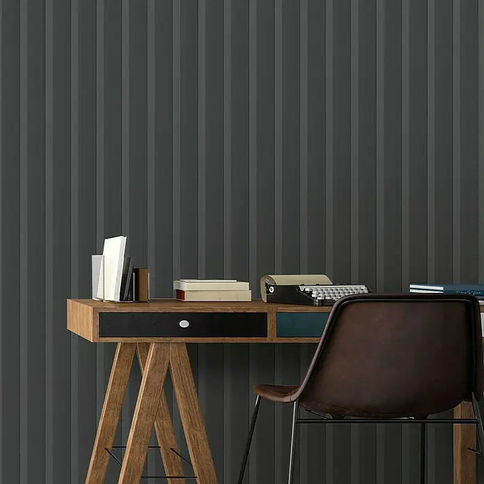 FN Neuhofer Wandpaneel Wally WA100 - Eiche schwarz, 2.670 x 118 x 12 mm - Ein stilvoller Schreibtisch mit einer Schreibmaschine und Büchern, ergänzt durch einen modernen Stuhl vor einer grauen Wandpaneele-Tapete.