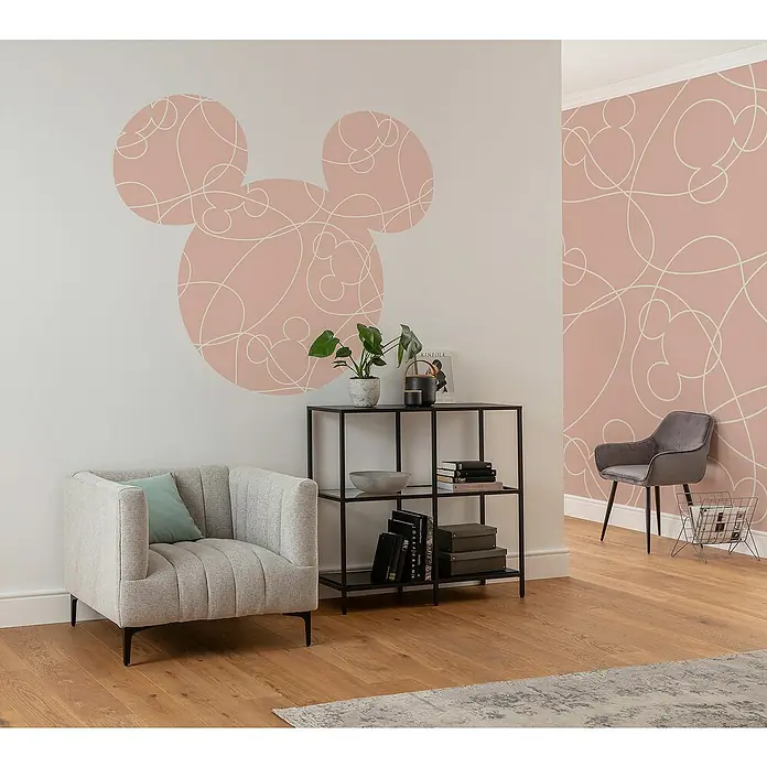 Komar Dots Fototapete rund Disney Mickey Head Knotted - 128 cm, Selbstklebend - Eine moderne Wohnzimmerszene mit einem eleganten grauen Sessel, einem stilvollen Bücherregal und einer verspielten Mickey-Mouse-Wanddekoration.