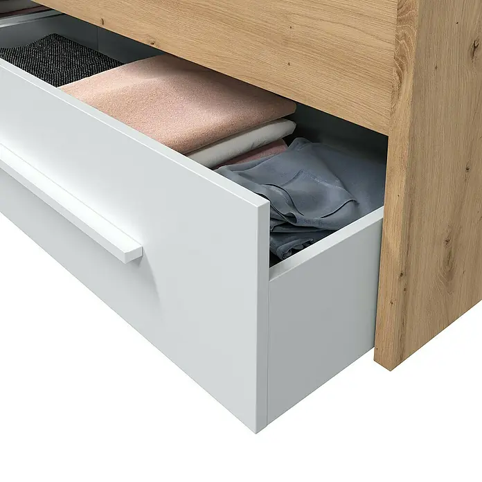 Armario para ropa y cama Noa - Roble Nodi/Blanco Artik - Cajón de un armario con ropa doblada de diferentes colores y texturas.