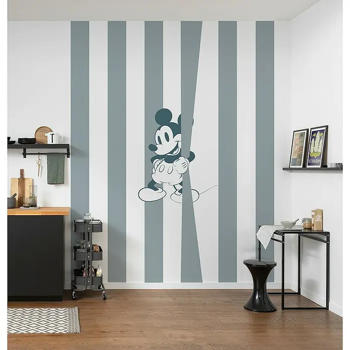 Komar Fototapete Mickey Offbeat - B x H: 250 x 200 cm, Vlies - Wand mit einem Mickey Mouse Wandbild mit grauen Streifen im Hintergrund und einem kleinen Küchentisch und Stuhl.