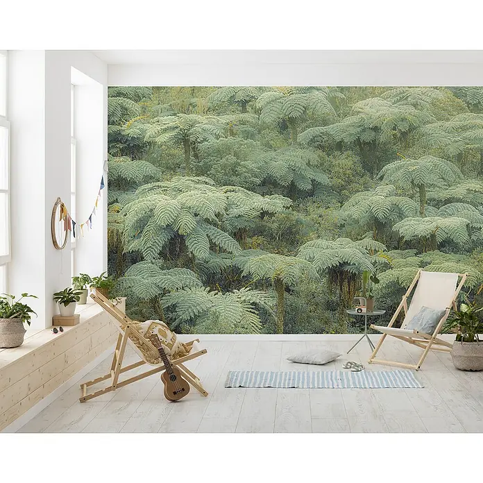 Komar Pure 2 Fototapete Jungle Lands - B x H: 400 x 250 cm, Vlies - Dieses Bild zeigt eine entspannende Raumszene mit einem großen Wandbild von Farnbäumen, ergänzt durch Liegestühle und Zimmerpflanzen.