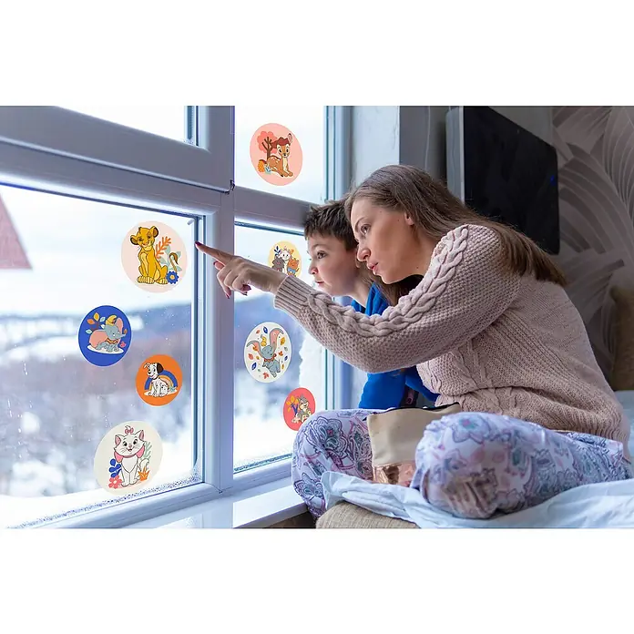 Komar Fenstersticker Disney Better Together Bubbles - 30 x 30 cm - Mutter und Kind betrachten bunte Fensteraufkleber mit Disney-Motiven, die eine fröhliche und verspielte Atmosphäre im Raum schaffen.