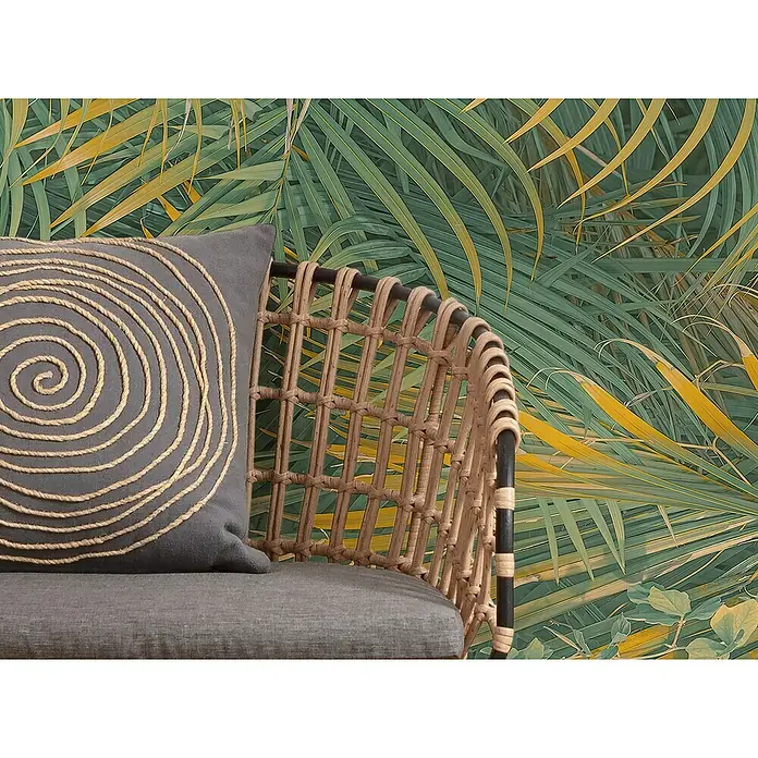 Komar Pure 2 Fototapete Neon Fern - B x H: 200 x 250 cm, Vlies - Nahaufnahme eines grauen Sofakissen mit einem spiralförmigen Seildesign auf einem Rattansessel vor einem tropischen Blätterhintergrund.