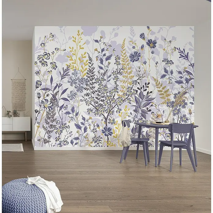Komar Pure 2 Fototapete Bloomique - B x H: 400 x 250 cm, Vlies - Ein Essbereich mit einem lilafarbenen Tisch und Stühlen vor einer floralen Wandtapete, ergänzt durch einen Strickhocker im Vordergrund.