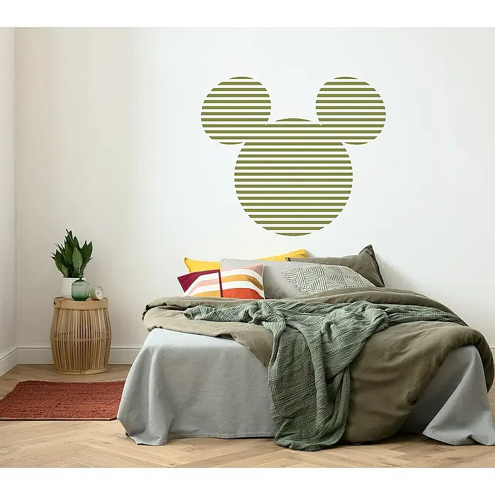 Komar Dots Fototapete rund Disney Mickey Head Stripes - 128 cm, Selbstklebend - Eine Wanddekoration mit einem olivgrünen, gestreiften Mickey-Mouse-Motiv über einem gemütlichen Bett in einem stilvollen Schlafzimmer.