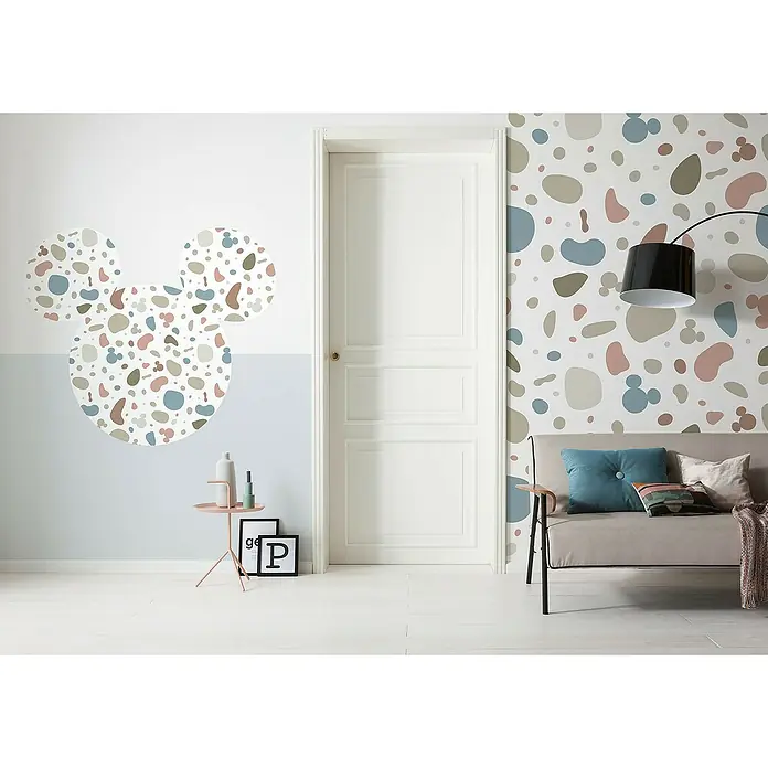 Komar Dots Fototapete rund Mickey Head Terrazzo Bambino - 128 cm, Selbstklebend - Ein stilvolles Interieur mit einer weißen Tür, einem Sofa mit Kissen und einem Beistelltisch. Das abstrakte Design an der Wand verleiht eine verspielte Note.
