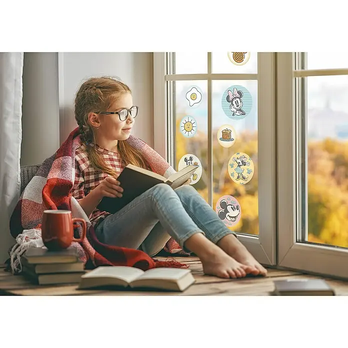 Komar Fenstersticker Disney Mickey Rise and Shine Bubbles - 30 x 30 cm - Ein gemütliches Mädchen liest am Fenster mit verspielten Disney-Aufklebern und einer warmen Tasse Tee. Das bezaubernde Ambiente lädt zum Verweilen ein.