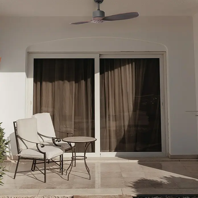 Sulion Ventilador de techo Dual Outdoor - Nogal, 106 cm, 14 W - Ventilador de techo sobre un patio con sillas y una mesa. El ventilador proporciona un flujo de aire cómodo en el área exterior.