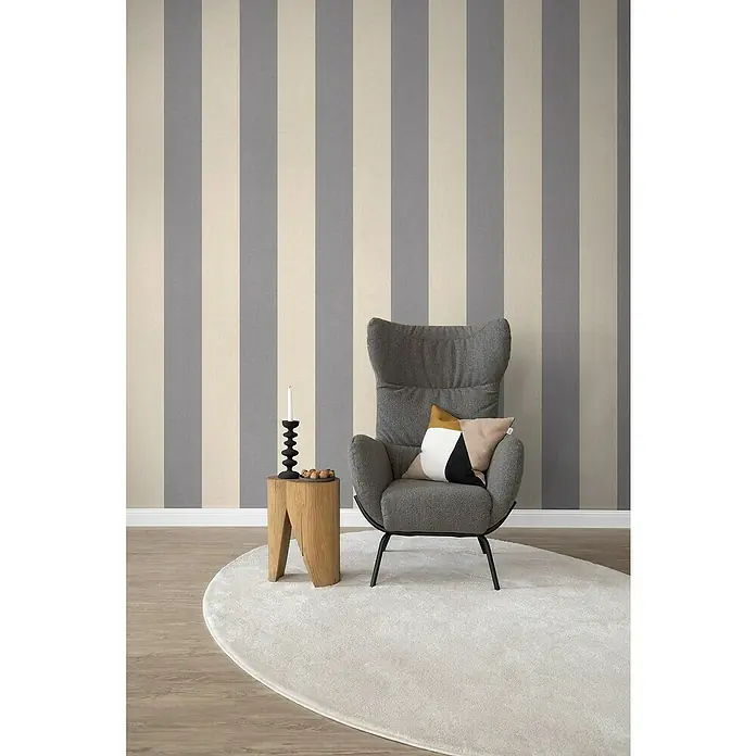 SCHÖNER WOHNEN-Kollektion Cosyliving Fototapete Streifen - B x H: 212 x 300 cm, Vlies, Grau-Creme - Einrichtungsidee mit einem grauen Sessel, einem Holzbeistelltisch, einer Kerze und einem ovalen Teppich vor einer gestreiften Wand.