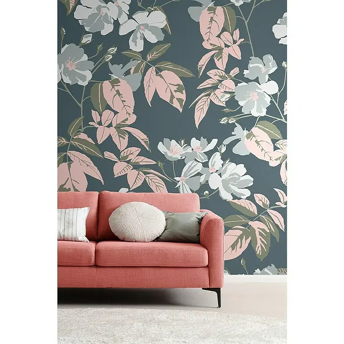 SCHÖNER WOHNEN-Kollektion Cosyliving Fototapete Blumen - B x H: 265 x 300 cm, Vlies, Blau-Rosa - Nahaufnahme eines korallenroten Sofas mit Kissen vor einer Wand mit floralem Muster, das eine stilvolle und komfortable Wohnatmosphäre ausstrahlt.