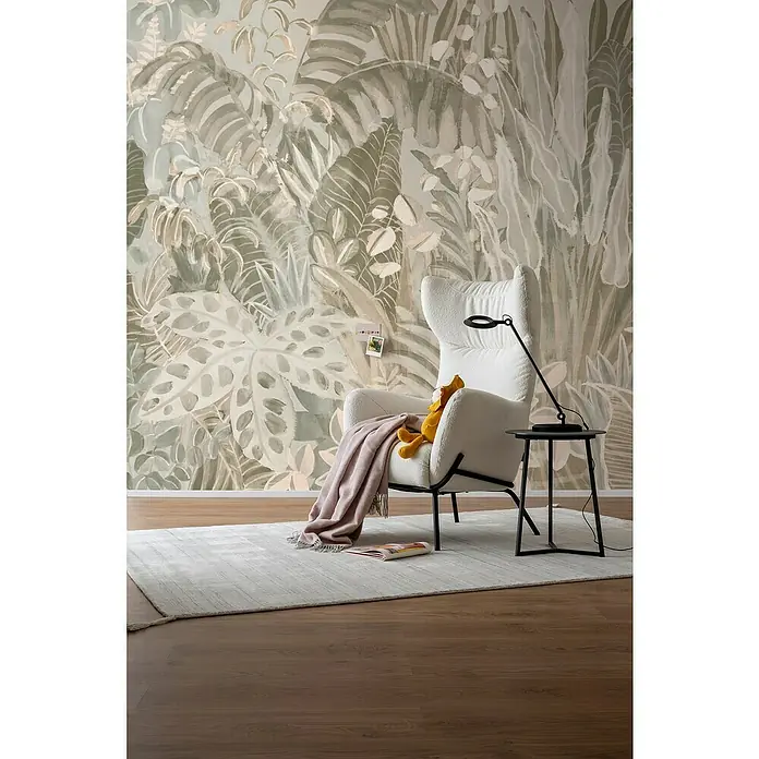 SCHÖNER WOHNEN-Kollektion Cosyliving Fototapete Blätterwald - B x H: 318 x 300 cm, Vlies, Oliv-Grau - Wohnzimmer-Szene mit einem eleganten weißen Sessel, einer stilvollen Stehlampe und einem dekorativen Beistelltisch vor einer tropischen Tapete.