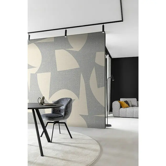 SCHÖNER WOHNEN-Kollektion Cosyliving Fototapete Abstrakt-Geometrisch - B x H: 265 x 300 cm, Vlies, Grau-Beige - Das Bild zeigt eine moderne Raumgestaltung mit einem stilvollen grauen Sessel und einem runden Teppich, hervorgehoben durch eine auffällige geometrische Wand.