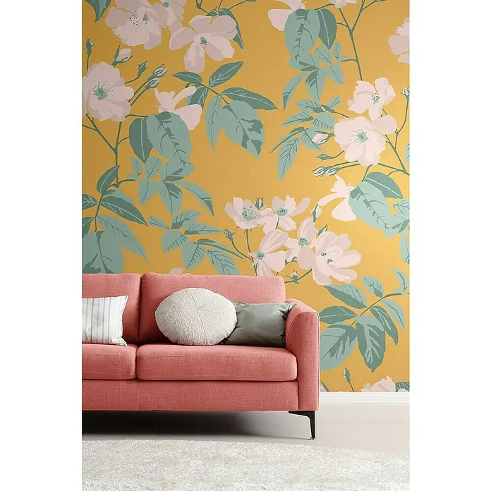SCHÖNER WOHNEN-Kollektion Cosyliving Fototapete Blumen - B x H: 265 x 300 cm, Vlies, Gelb-Rosa - Nahaufnahme eines lachsfarbenen Sofas mit Zierkissen vor einer auffälligen floralen Tapete, die eine gemütliche und stilvolle Wohnatmosphäre schafft.