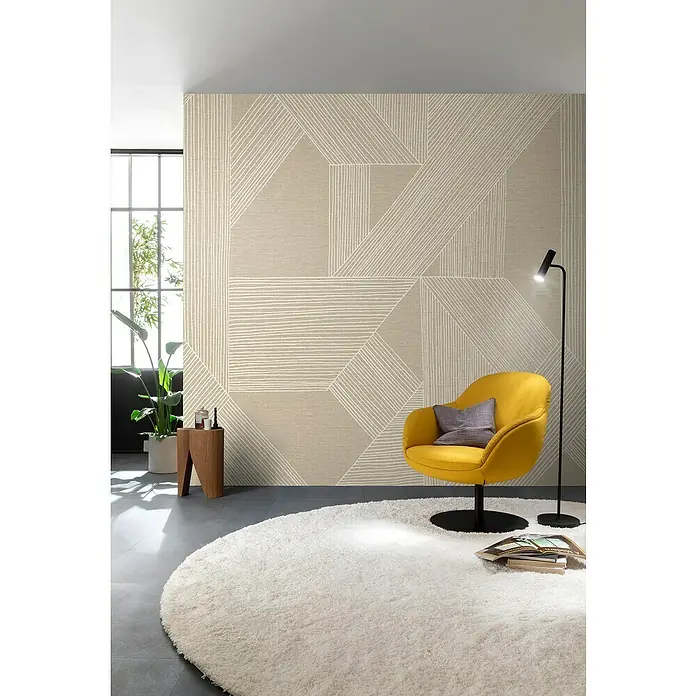 SCHÖNER WOHNEN-Kollektion Cosyliving Fototapete Linien - B x H: 265 x 300 cm, Vlies, Creme-Weiß - Gelber Sessel auf rundem Teppich mit Bücher und Stehlampe vor einer geometrisch gemusterten Wand.
