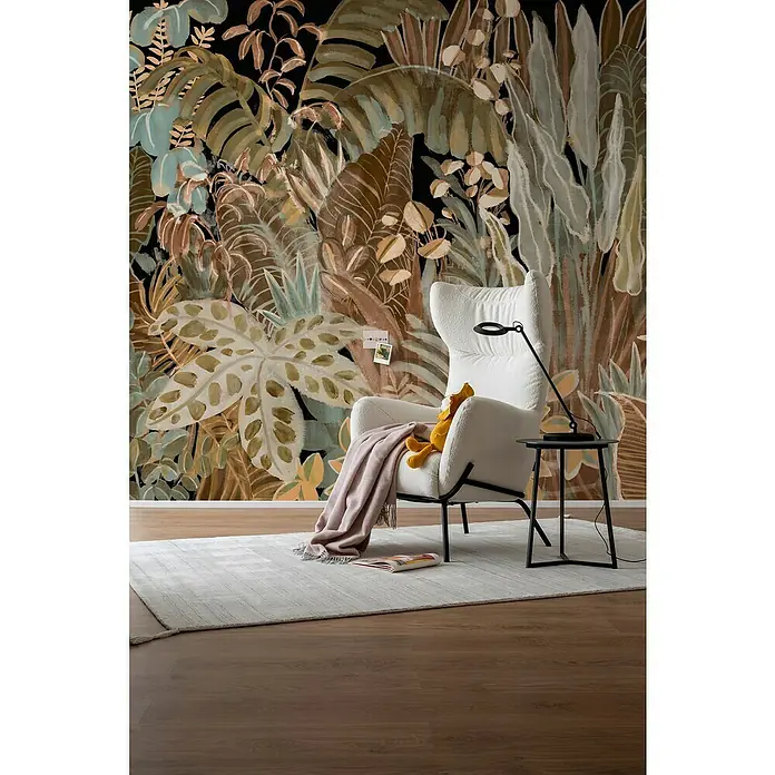 SCHÖNER WOHNEN-Kollektion Cosyliving Fototapete Blätterwald - B x H: 318 x 300 cm, Vlies, Terra-Mehrfarbig - Wohnzimmer mit einem bequemen Sessel, einem Beistelltisch und einem Teppich vor einer Dschungeltapete.