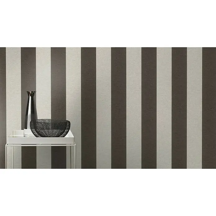 SCHÖNER WOHNEN-Kollektion Cosyliving Vliestapete STRIPE - Schwarz-Grau, Streifen, 10,05 x 0,53 m - Nahaufnahme eines Tisches mit einer Vase und einer Schale darauf, vor einem Hintergrund mit braunen und beigen Streifen.