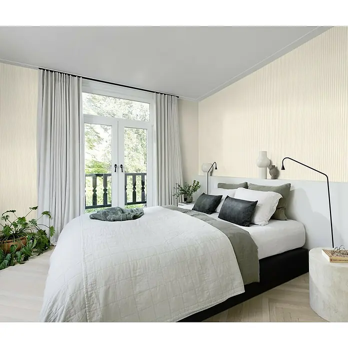 SCHÖNER WOHNEN-Kollektion Cosyliving Vliestapete LODGE Rundholz - Beige-Creme, Holzoptik, 10,05 x 0,53 m - Ein Schlafzimmer mit stilvoller Tapete, einem gemütlichen Bett und einem Fenster mit Vorhängen für ein entspanntes Ambiente.