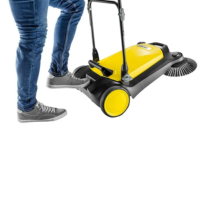 Kärcher Handkehrmaschine S 4 Twin - Flächenleistung: 2.400 m²/h, 20 l - Gelb-schwarze Kehrmaschine mit Rädern und Griff, die von einer Person in Jeans und grauen Schuhen bedient wird.