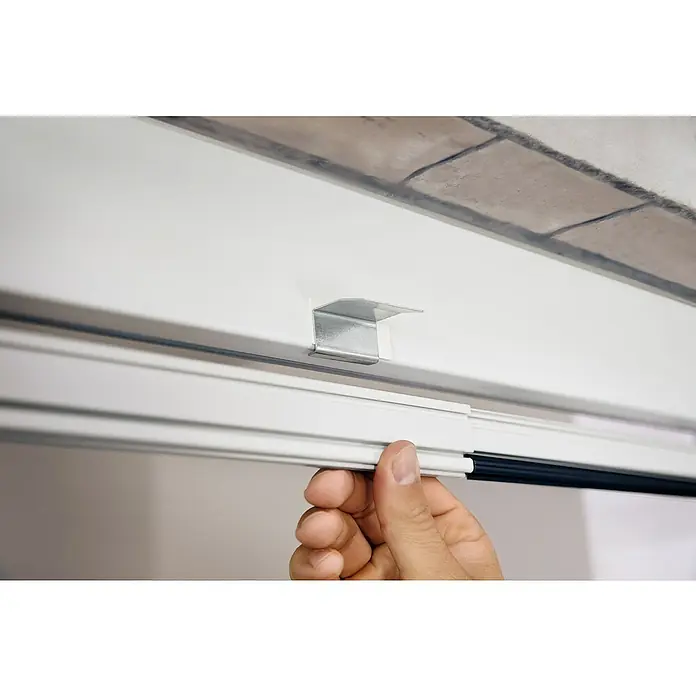 Tesa Insect Stop Puerta con protección contra insectos Falt - Blanco, Montaje de la mosquitera: Pinzas - Primer plano de un mecanismo de persiana enrollable que muestra una solución sencilla y eficiente para cubrir ventanas.\n