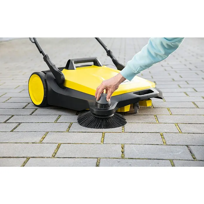 Kärcher Handkehrmaschine S 6 - Flächenleistung: 2.500 m²/h, 38 l - Der Kärcher S 650 2-in-1 Kehrmaschine im Einsatz, mit gelbem Gehäuse und schwarzen Bürsten, reinigt eine gepflasterte Fläche effektiv.
