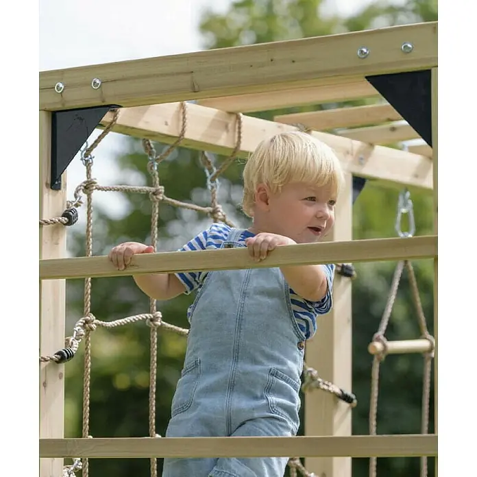Swing King Kinderspielturm Jack - L x B x H: 210 x 100 x 215 cm, Holz - Ein kleiner Junge in Latzhose klettert auf ein hölzernes Spielgerät mit Seilen und Leitern, umgeben von Grün.