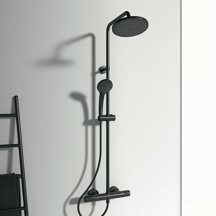 Ideal Standard Ceratherm Duschsystem T25 - Mit Thermostatarmatur, Höhe: 111 cm, Anzahl Strahlarten: 1 Stk. - Bild einer schwarzen Duschgarnitur mit rundem Kopf und Handbrause an einer weißen Wand.
