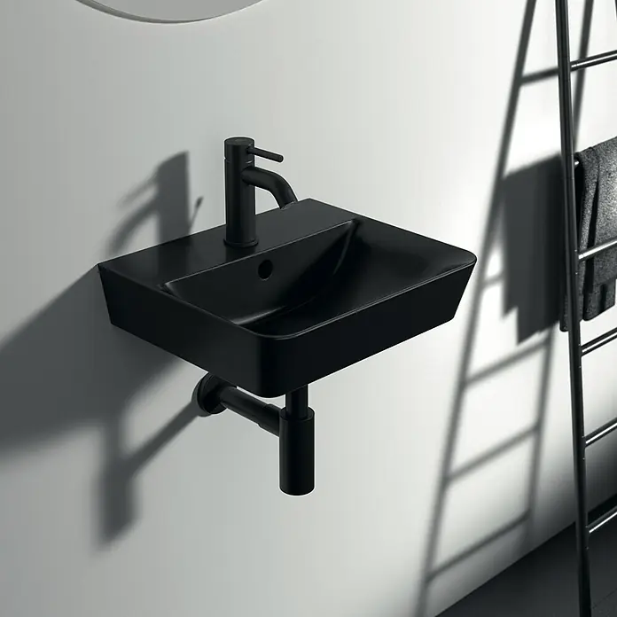 Ideal Standard Ceraline WaschtischarmaturSchwarz, Matt, Mit Ablaufgarnitur - Schwarzes Waschbecken mit Armatur an einer weißen Wand, daneben eine Handtuchleiter. Schlichtes und modernes Design für jedes Badezimmer.