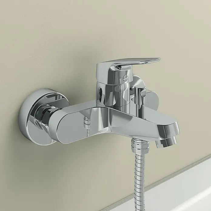 Ideal Standard Ceraflex Badewannenarmatur - Ausladung Armatur: 162 mm, Chrom, Glänzend - Nahaufnahme eines glänzenden, verchromten Badewannenmischers mit Schlauch und Hebel, der an einer beigen Wand montiert ist.