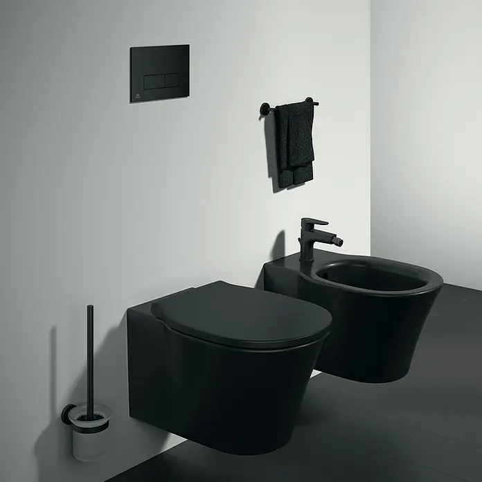 Ideal Standard Connect Air Wand-WC - Spülrandlos, Ohne Spezialglasur, Spülform: Tief, WC Abgang: Waagerecht, Schwarz - Schwarze wandhängende Toilette und Bidet mit passender Bürste und Handtuchhalter schaffen ein modernes Badezimmerdesign.