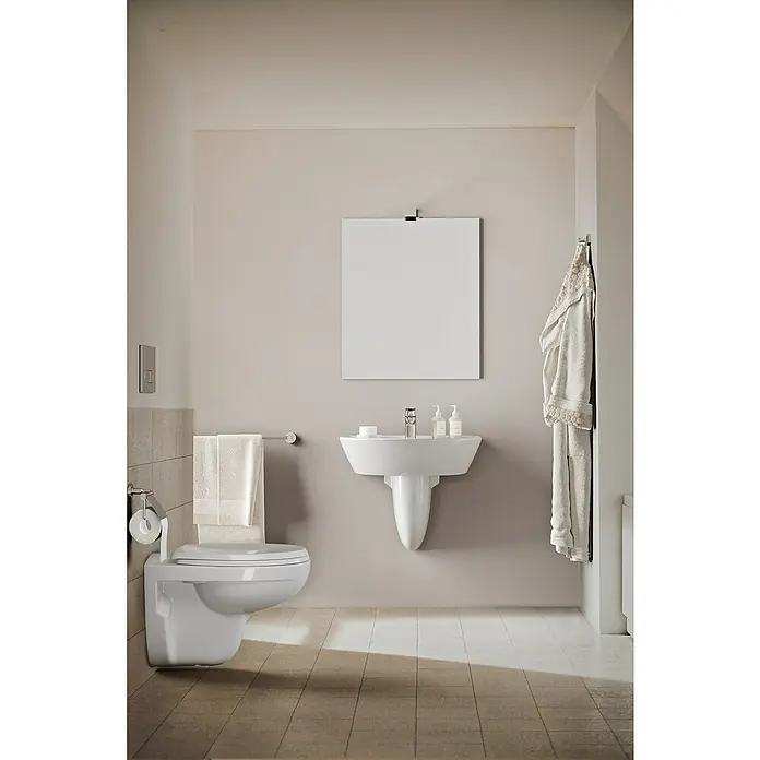 Ideal Standard Ceraflex Waschtischarmatur - Höhe: 13,3 cm, Chrom, Glänzend - Ein minimalistisches Badezimmer mit einer wandhängenden Toilette, einem Waschbecken und einem Spiegel, die ein sauberes und modernes Ambiente schaffen.