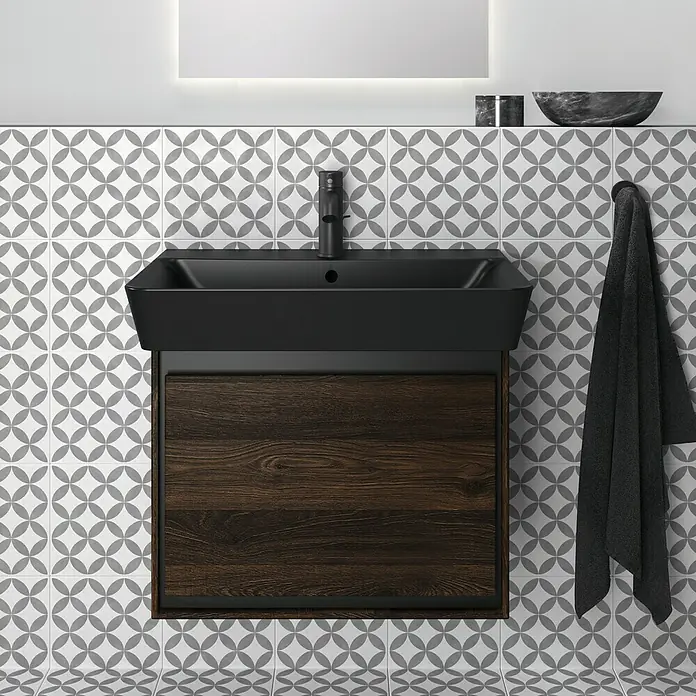 Ideal Standard Ceraline WaschtischarmaturSchwarz, Matt, Mit Ablaufgarnitur - Modernes Badezimmerwaschbecken mit schwarzer Beckenoberfläche und Holzschrankfront, ergänzt durch eine graue Handtuchaufhängung.
